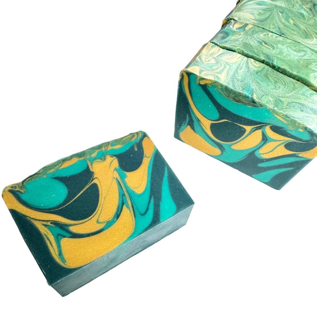 Handmade Mosswood soap bar by Dirty Little Suds with green and gold swirls, scented with pine, birch, cedarwood, and cypress.”