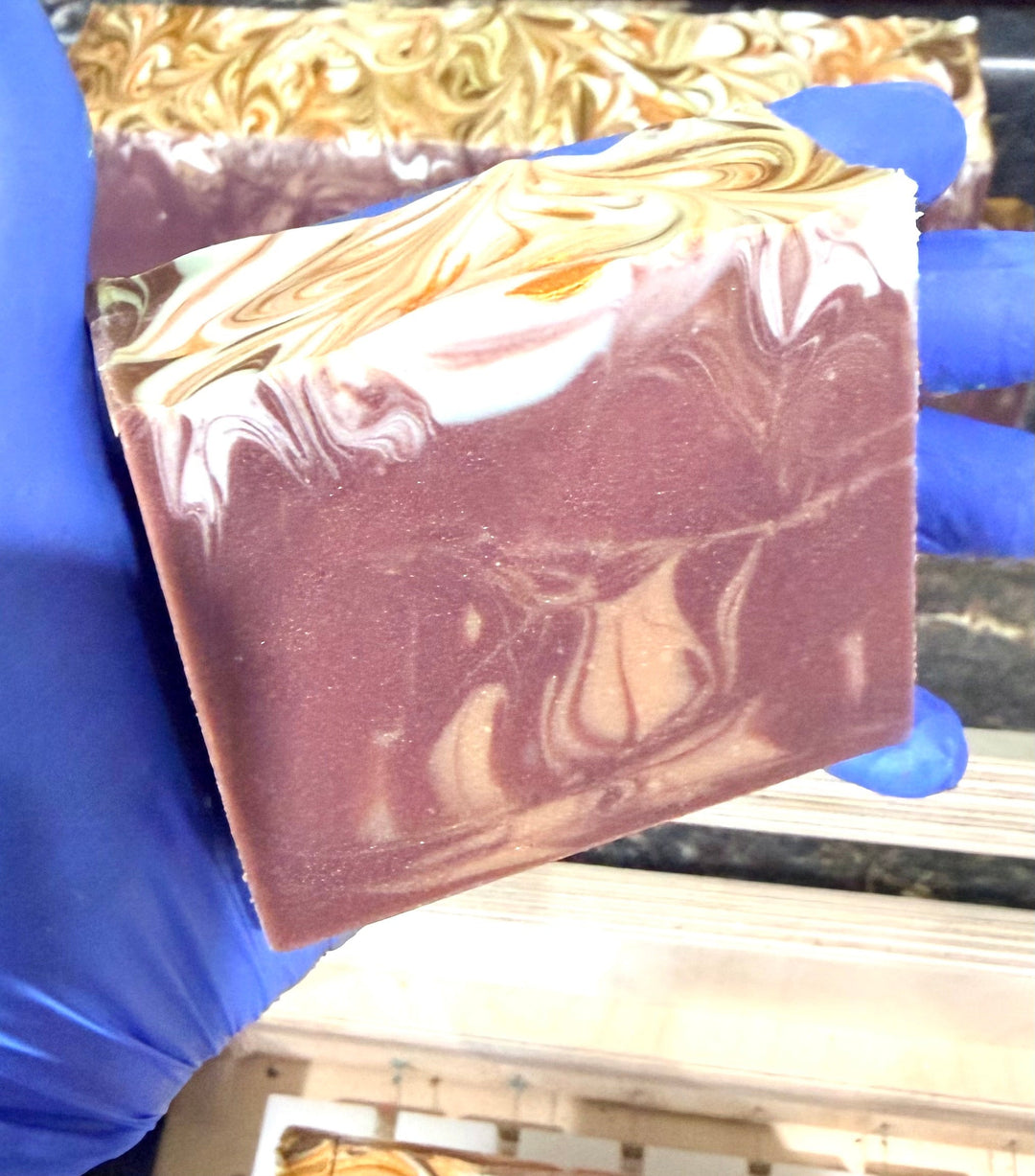 Freshly cut handmade cold process soap bar held over the curing rack at Dirty Little Suds.