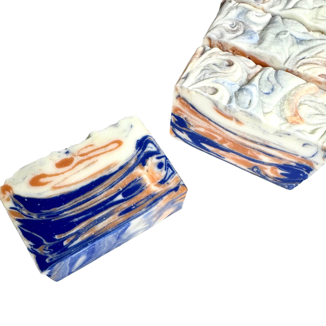 Handcrafted artisan soap bar with bold blue, orange, and white swirls, scented with fresh linen, cotton blossom, and citrus, Air Your Dirty Laundry by Dirty Little Suds.