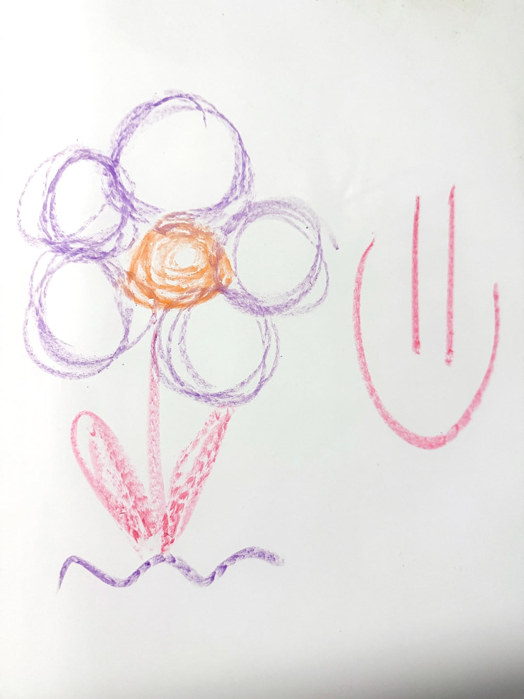 Bath Crayon doodles of a flower and smiley face on a white surface, showing smooth, colorful lines that easily wipe clean.