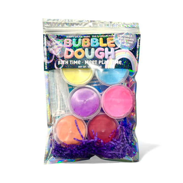 A holographic pouch of Bubble Dough by Dirty Little Suds, featuring six colorful 2 oz containers of reusable bath dough and purple crinkle paper packaging. Label reads “Bath Time – Meet Play Time.