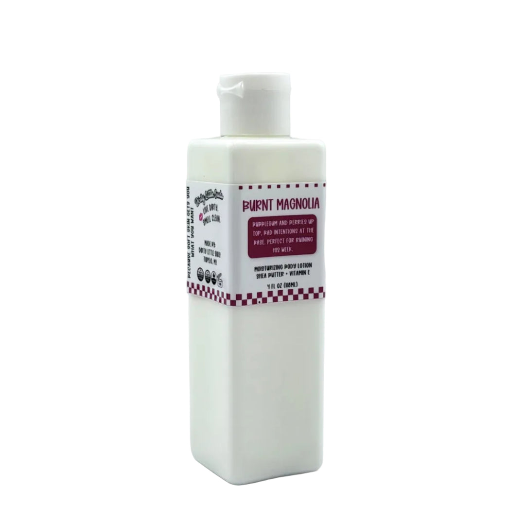 White rectangular 4 oz Dirty Little Suds body lotion bottle labeled Burnt Magnolia with pink retro checkered design on a clean white background