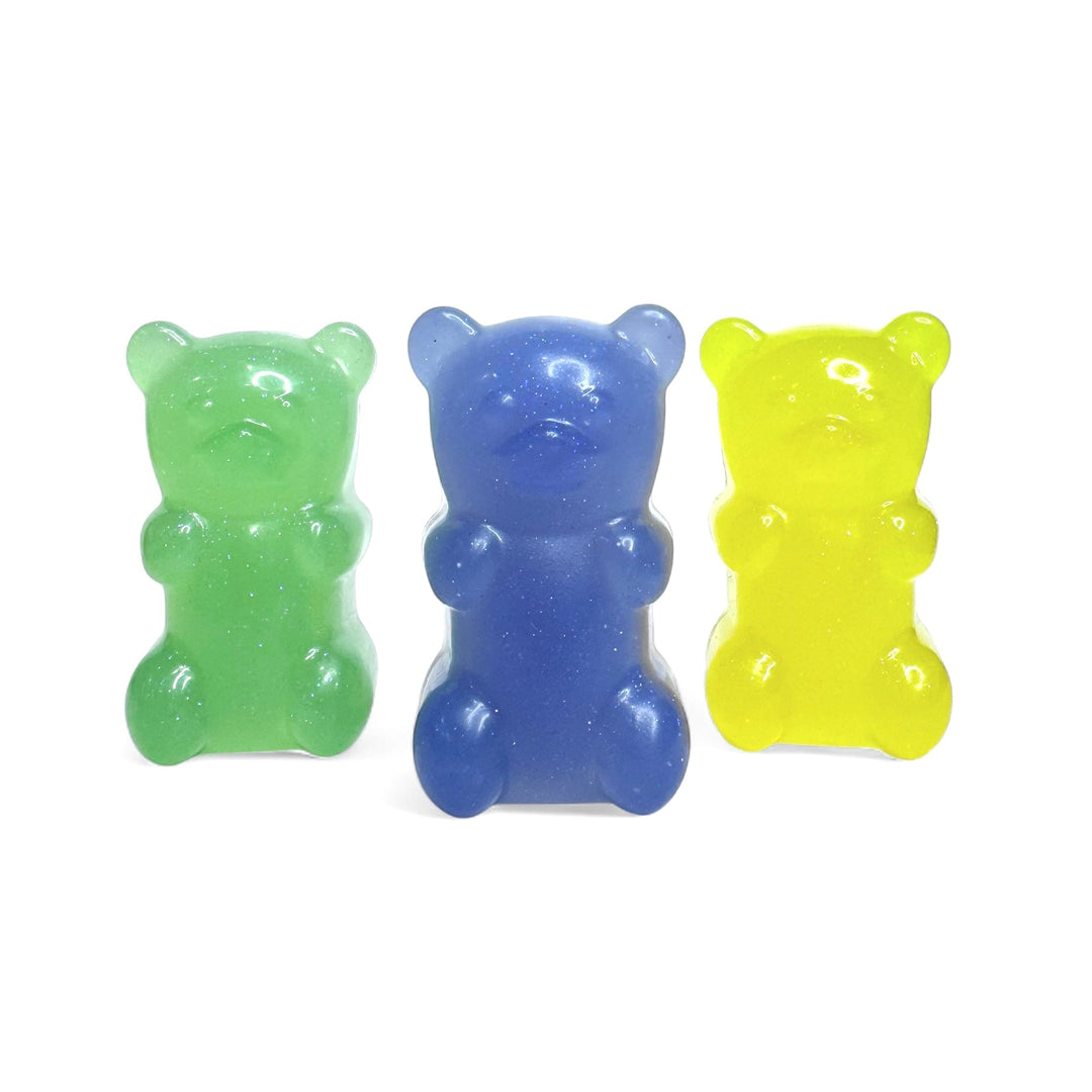 Set of three glitter gummy bear soaps by Dirty Little Suds on a white background. Green, purple, and yellow handmade soaps with eco-friendly glitter and fruity scents, available individually or in a 3 for $15 bundle.