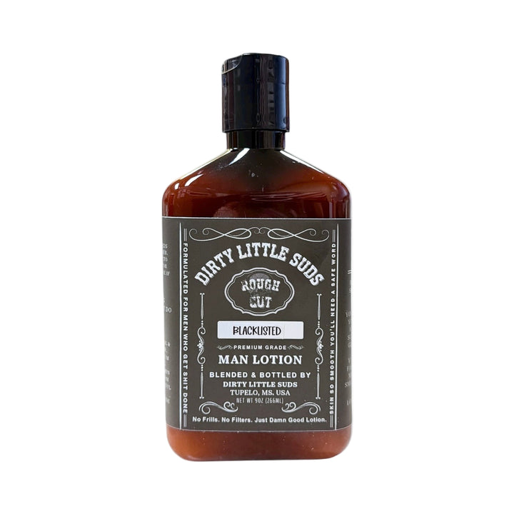 Amber bottle of Dirty Little Suds Rough Cut Men’s Lotion in the Blacklisted scent, featuring bold matte black label. A clean, salty, masculine lotion made for men who get things done.