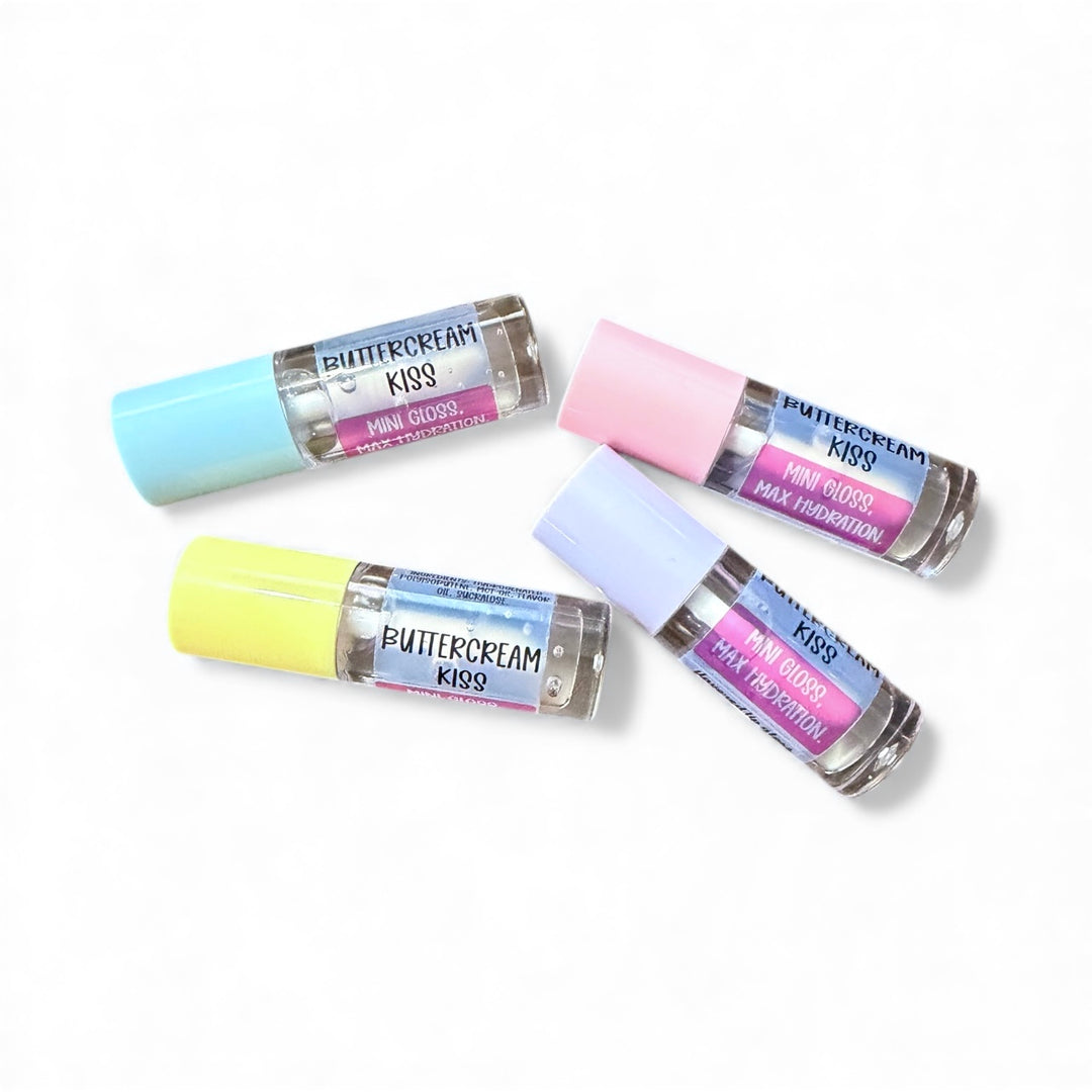 Four mini Buttercream Kiss lip oil tubes with pastel caps in blue, pink, yellow, and lavender, arranged on a white background | Dirty Little Suds