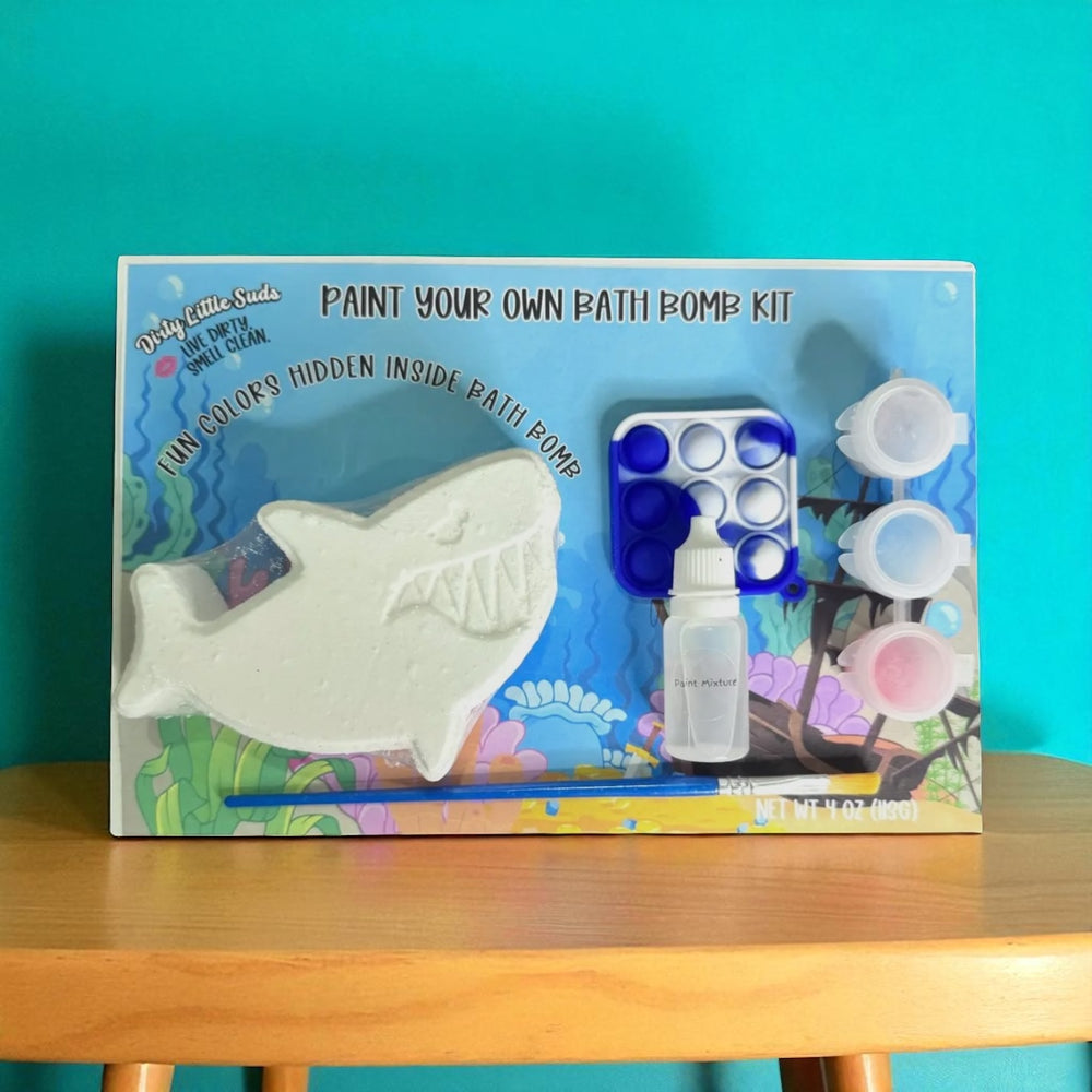 Dirty Little Suds Paint Your Own Bath Bomb Kit – shark bath bomb with hidden colors, paint set, fidget toy, and brush displayed against a teal background.