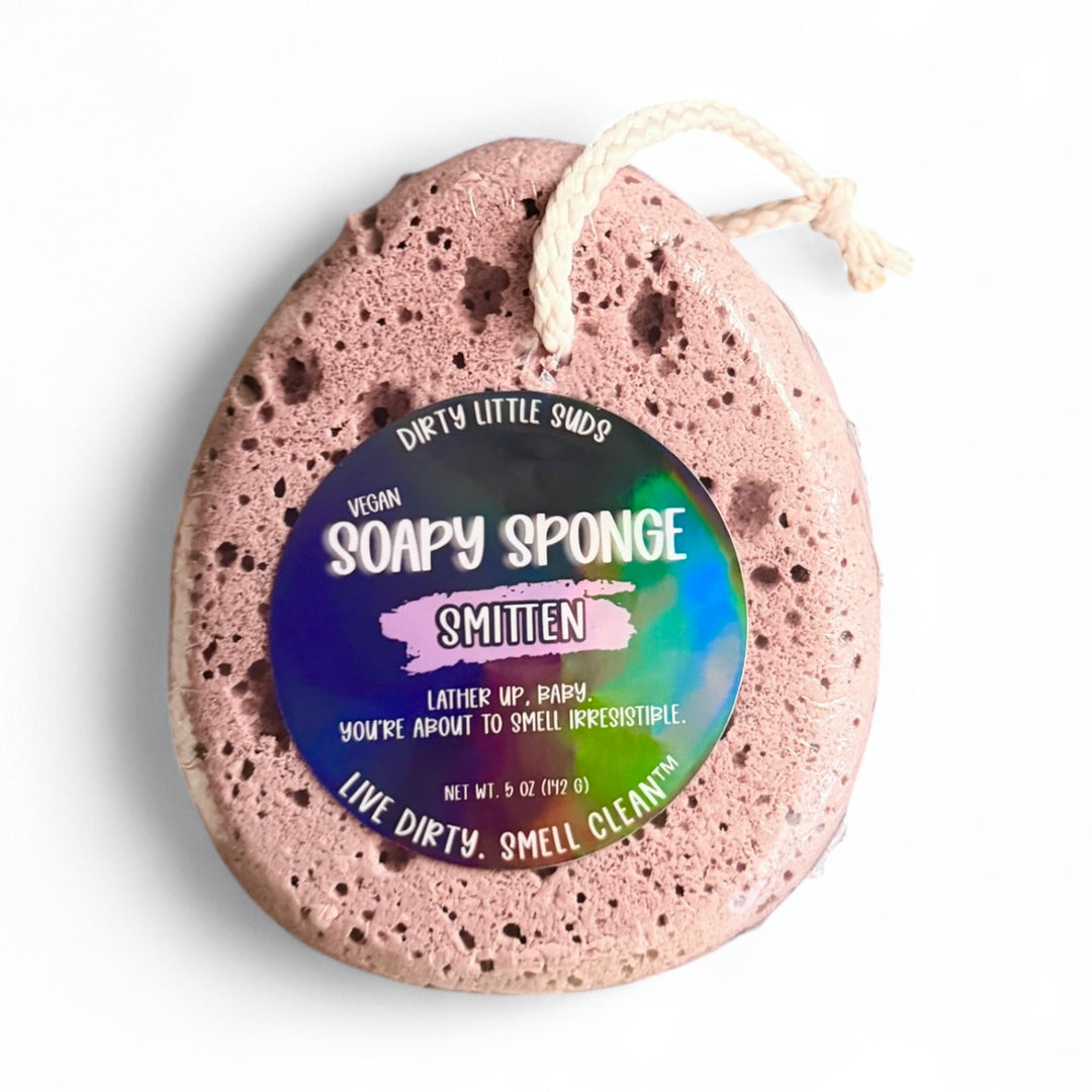 Dirty Little Suds Soapy Sponge in Smitten scent – mauve vegan sponge with holographic label, featuring notes of peach, berries, caramel, and ginger; sulfate, paraben, and phthalate free.