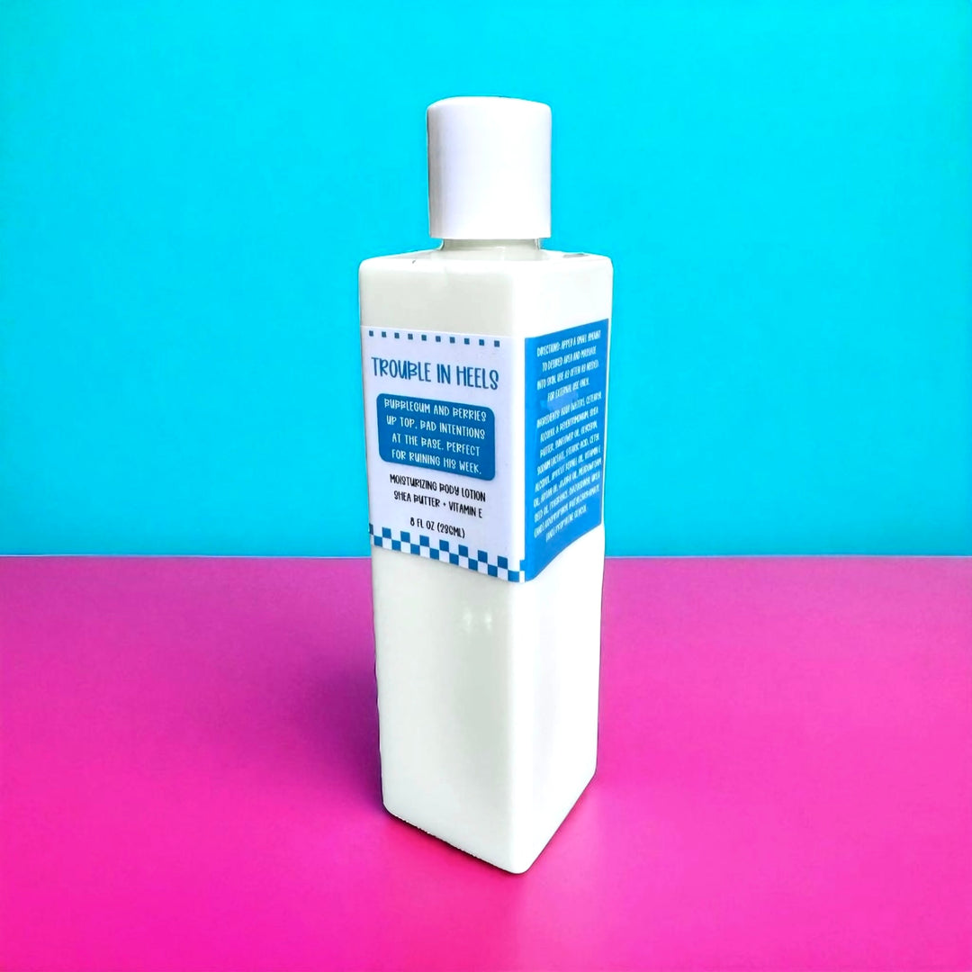 White rectangular 8oz bottle with a bright blue retro label reading “Bubblegum and berries up top. Bad intentions at the base. Perfect for ruining his week.” Shot on a turquoise and hot pink background.