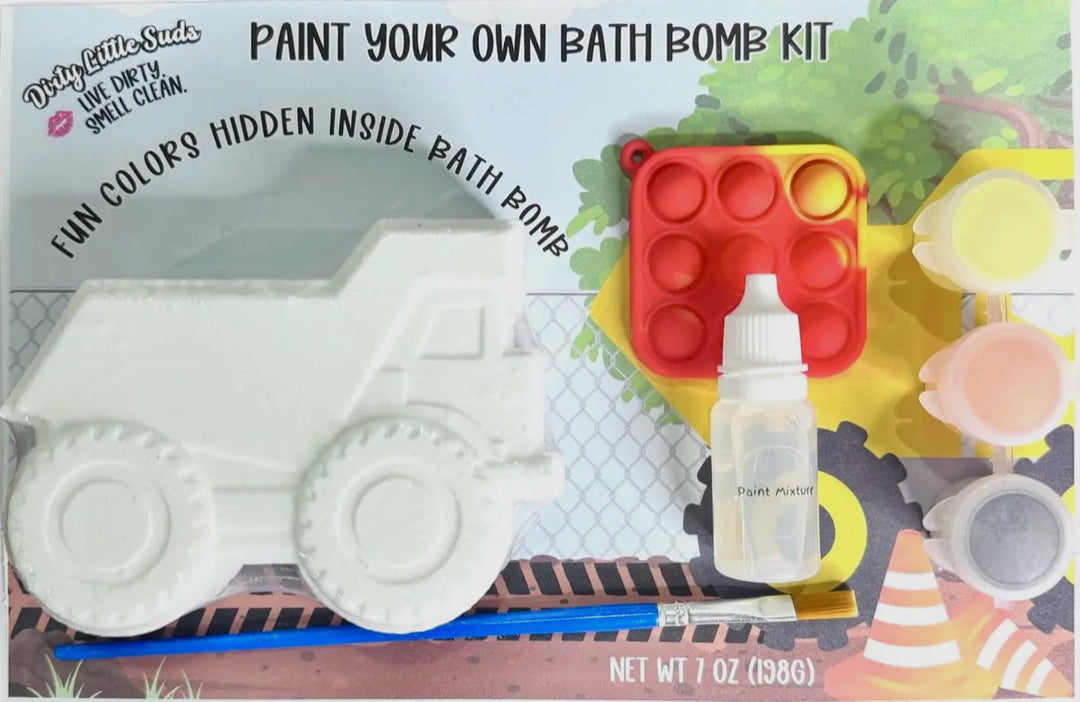 Dirty Little Suds Paint Your Own Bath Bomb Kit featuring a truck bath bomb, paint pots, brush, mixing dropper, and red pop-it fidget toy on construction-themed packaging.