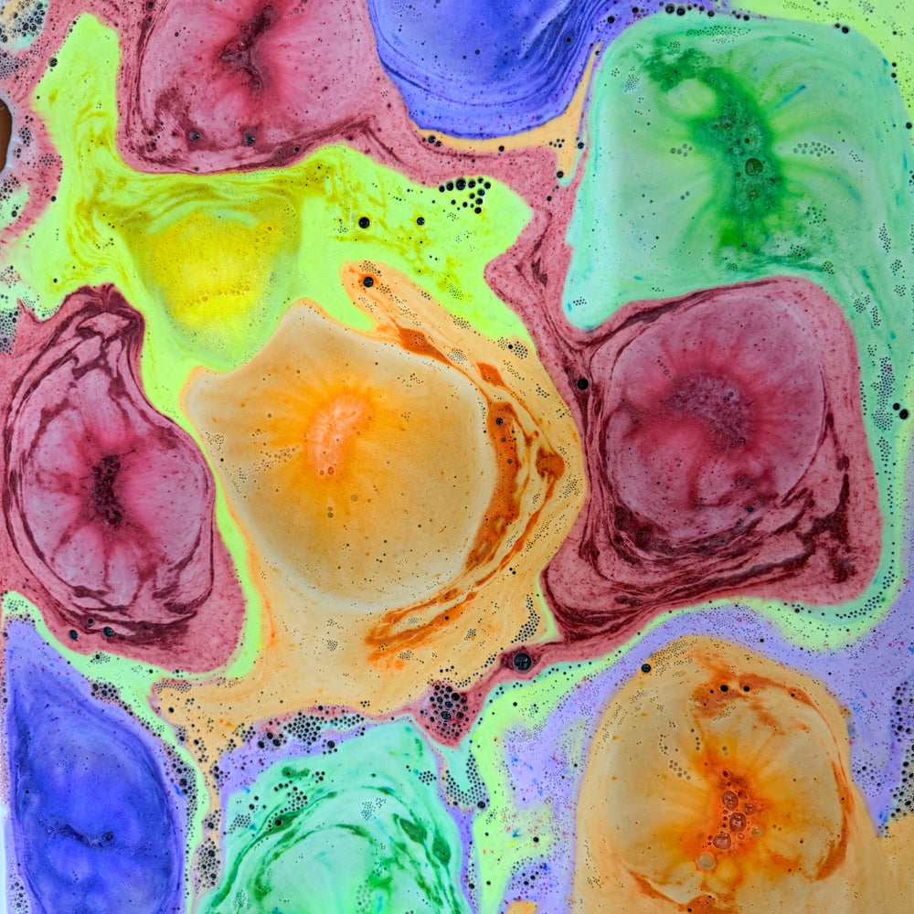 Color-changing jelly bean bath bombs creating vibrant swirls of pink, blue, yellow, purple and green in bath water