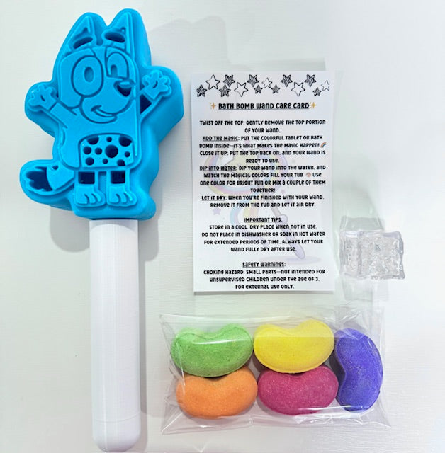 Contents of the Magic Bath Bomb Wand Kit by Dirty Little Suds displayed on white background. Includes a blue dog bath wand, five colorful jelly bean bath bombs, a flashing light cube, and care card.