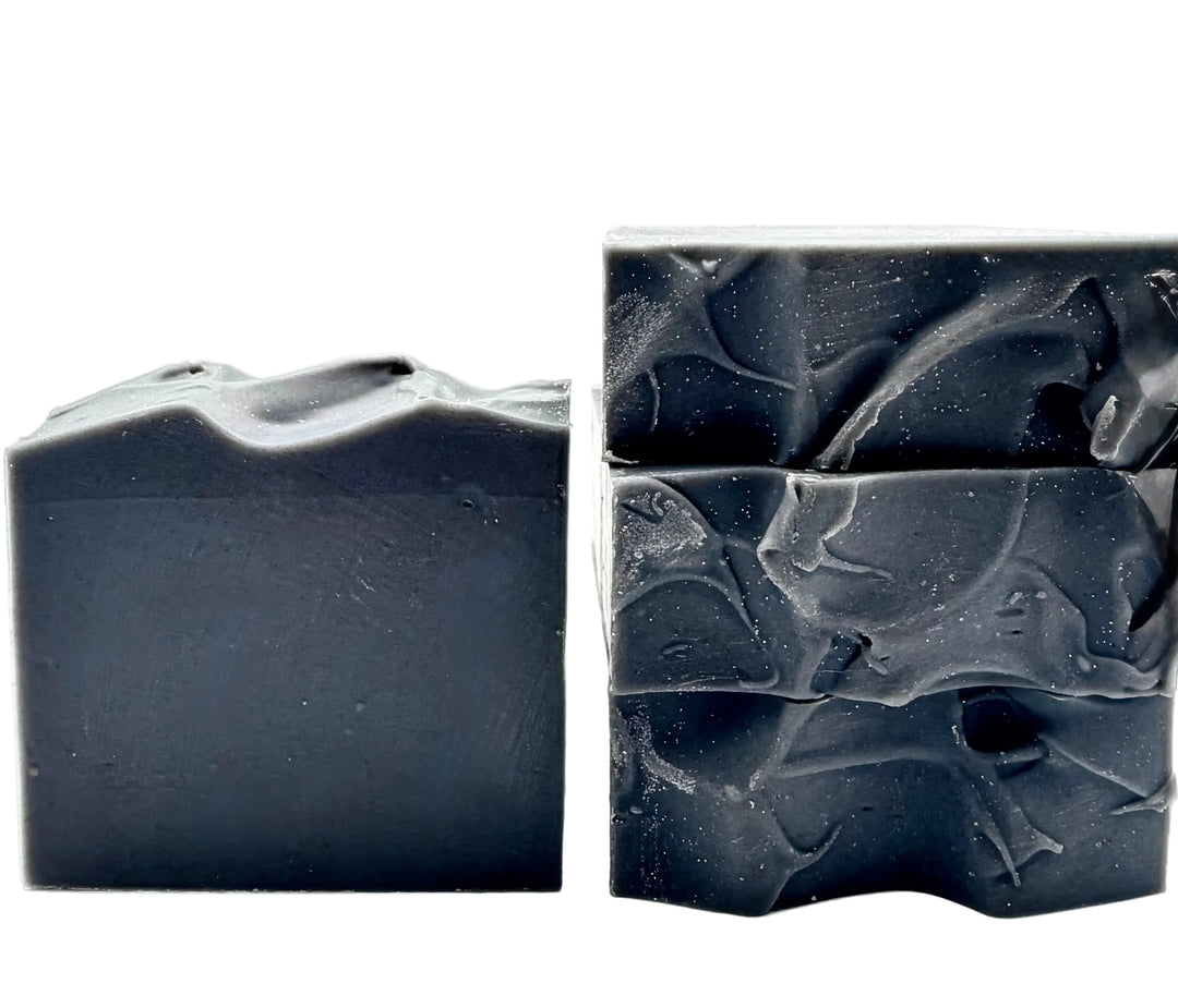 Dark charcoal gray handmade soap bars with textured tops and a moody, minimalist aesthetic