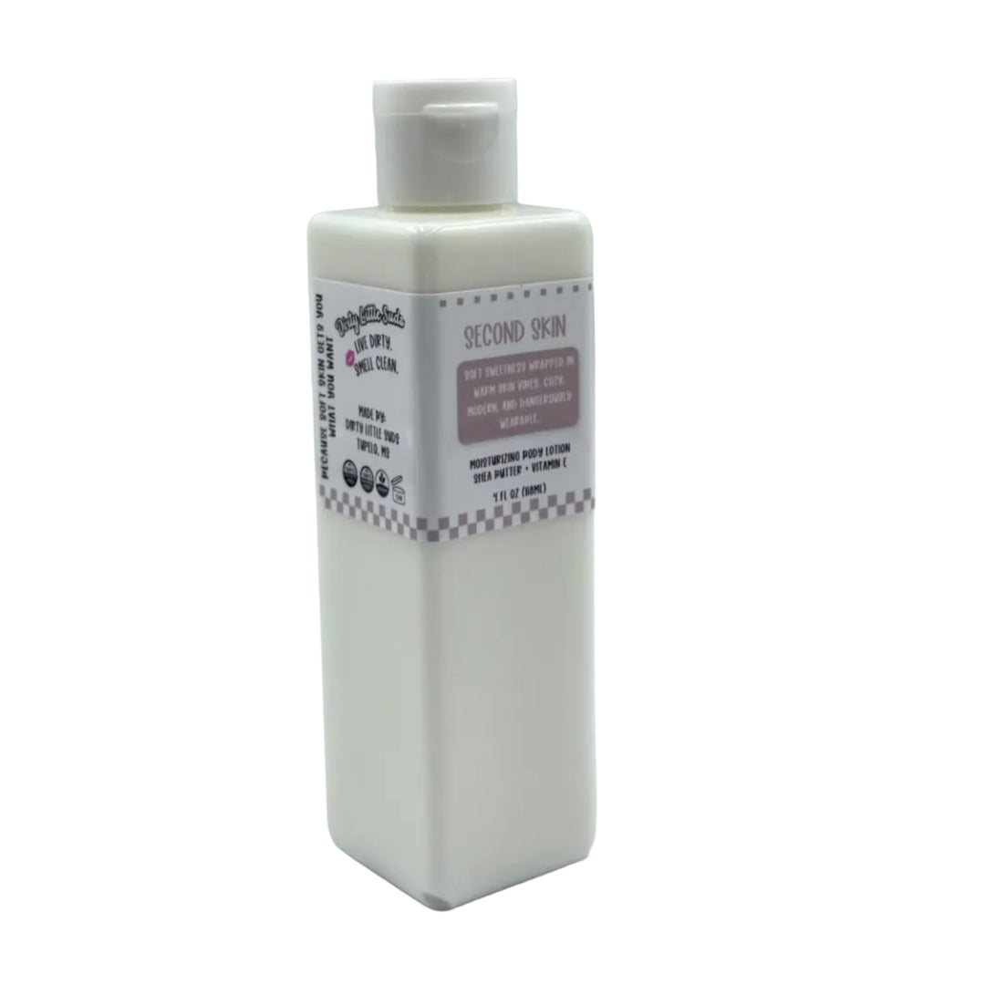 Dirty Little Suds Second Skin body lotion in a white rectangular bottle with flip-top cap and mauve label, featuring a warm vanilla and skin musk scent.