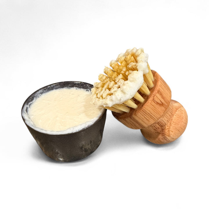 Wooden dish brush foaming on solid dish soap in dark ceramic ramekin – biodegradable lemon D-Limonene formula by Dirty Little Suds