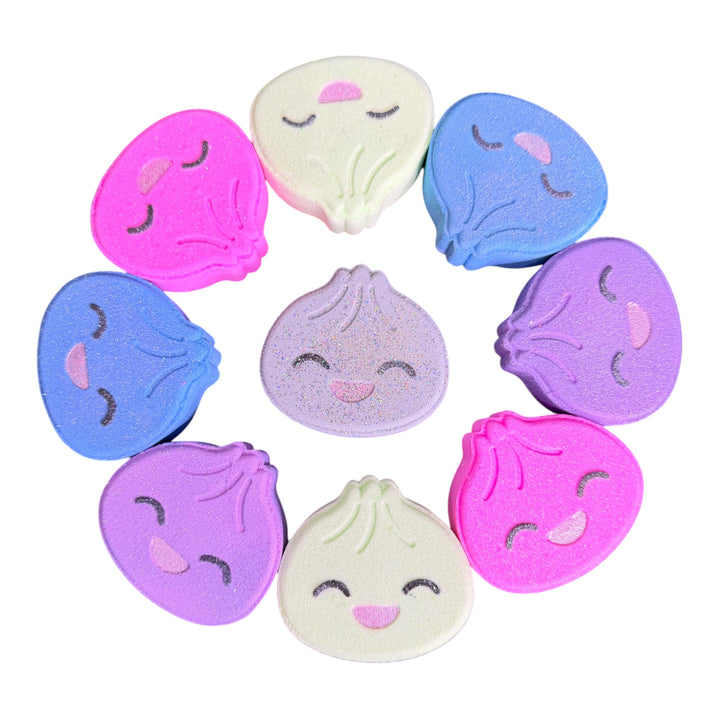 Colorful handmade Surprise Dumplin bath bombs in pink, purple, blue, green and white with hand-painted smiling faces.