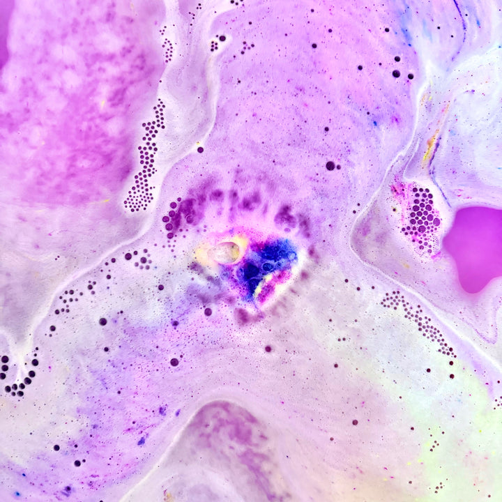 Unicorn Horn Bath Bomb fizzing and releasing colorful swirls into bath water made by Dirty Little Suds.
